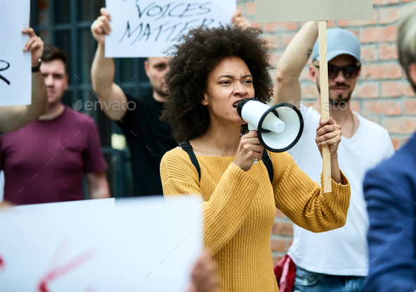 African American woman shouting through megaphone on anti-racism protest.
