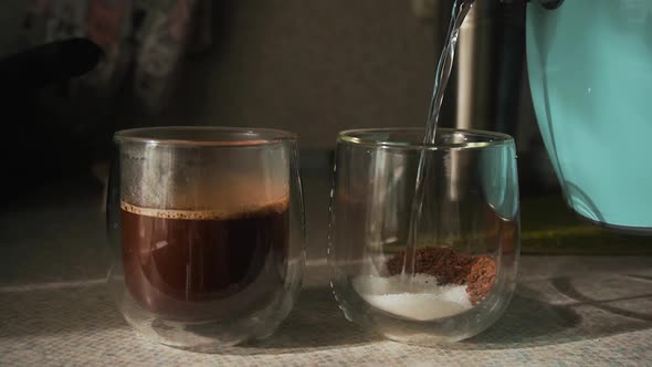 In Two Glasses with Double Bottom with Instant Coffee Sugar Pour Boiling Water From Turquoise Kettle