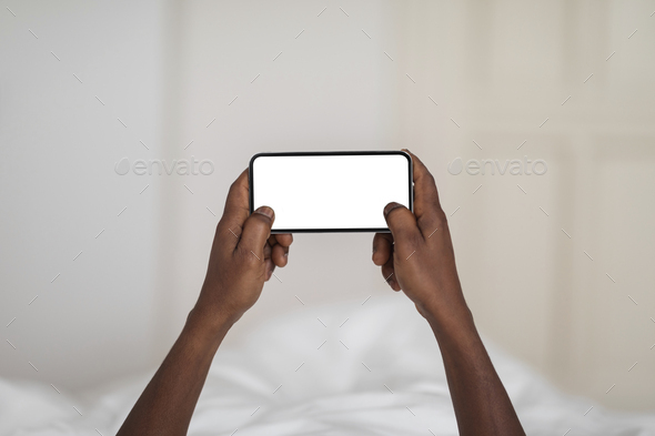 Mobile Gaming. Unrecognizable Black Male Using Blank Smartphone With White Screen, Mockup
