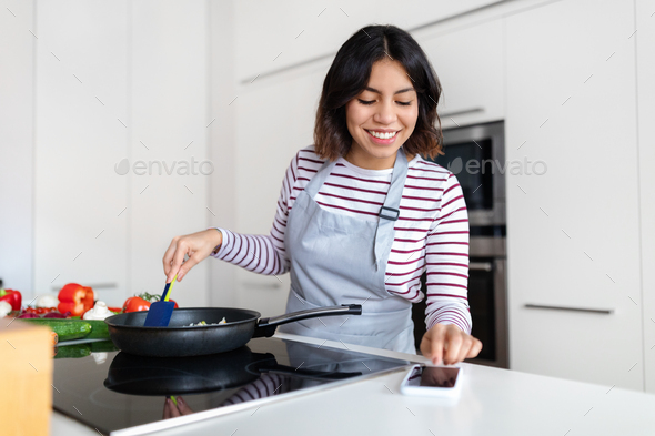 Cheerful lady reading culinary blog and cooking at home, mockup