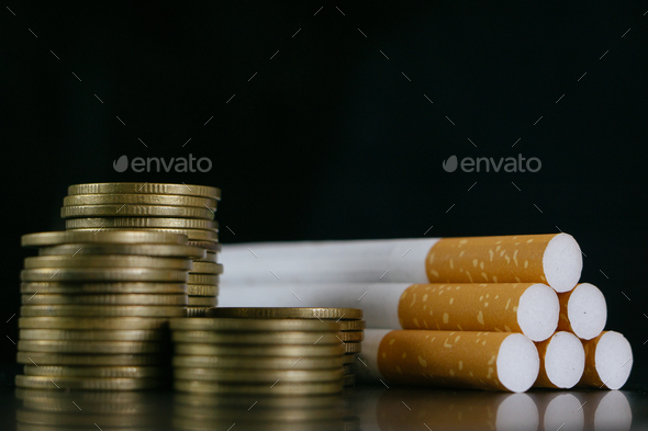 Tobacco Cigarettes and money coins.Cigarettes and TAX concept. Smoking is a waste of money.
