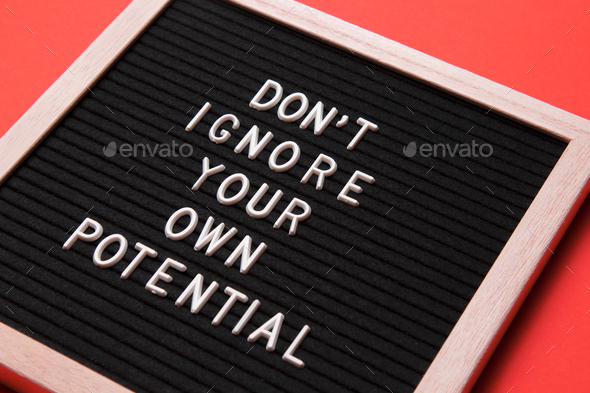 Motivational quote on black letter board on orange background.