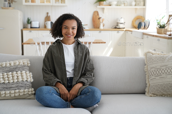 Relaxed calm young african american girl sits on couch in lotus pose in ...