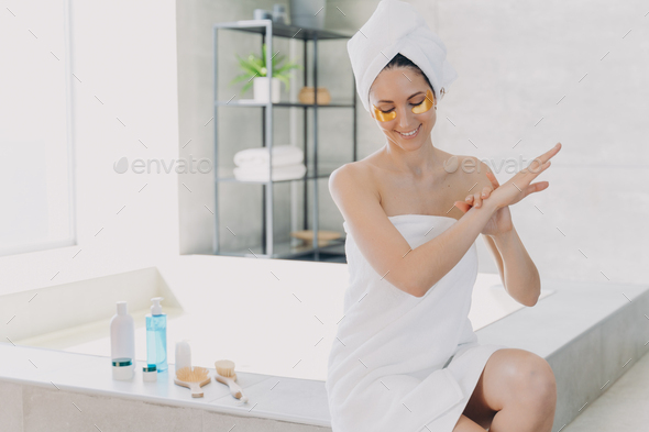 Lady applies eye patches and moisturizing skin with lotion. Relaxation at spa resort. - Stock Photo - Images