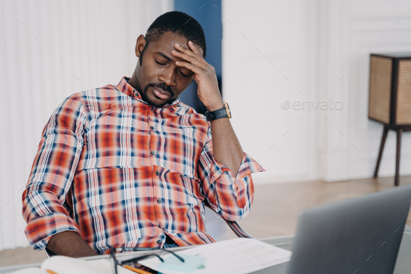 Tired african american man suffer headache at laptop thinking about business problem. Stress at work - Stock Photo - Images