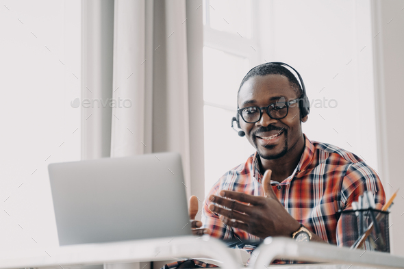 African american man wearing headset communicates with client by video call at laptop. Remote work - Stock Photo - Images