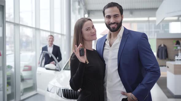 Young Wealthy Multiracial Family Posing in Car Dealership with Keys From New Automobile. Pretty alt