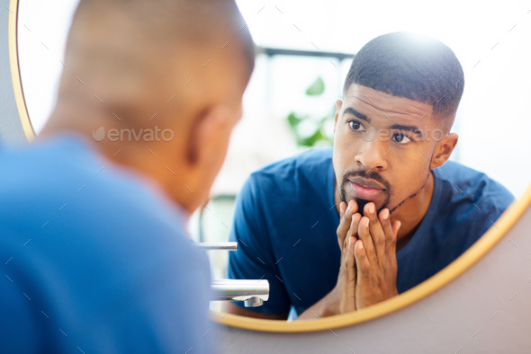 My new skincare routine has paid off. Shot of young man admiring his face in his bathroom mirror.