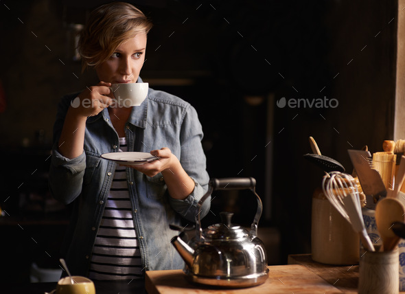Some quiet time with a cup of tea. Shot of an attractive young woman drinking tea in her kitchen.