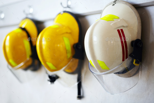 Protected against work hazards. Shot of firemens helmets hanging from a wall.