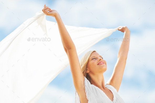 Feeling alive with vital energy. A beautiful young woman holding a scarf in the breeze.