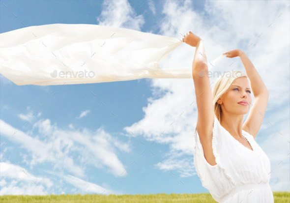 Finding freedom in the breeze. A beautiful young woman holding a scarf in the breeze. - Stock Photo - Images