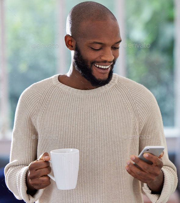 This app is so convenient. Shot of a young man drinking coffee while using a phone at home.