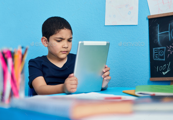 Shot of an adorable little boy using a digital tablet to complete a ...