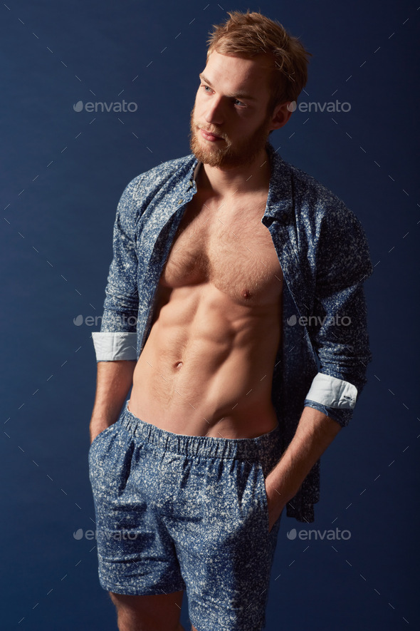 Casual yet masculine style. A muscular young man wearing an open shirt and looking away.