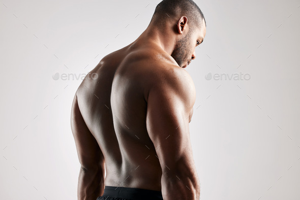Studio shot of a young muscular man posing against a grey background Stock  Photo by YuriArcursPeopleimages