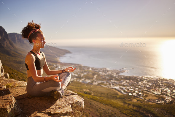 Find yourself and be that. Shot of a young woman meditating while sitting on a mountain cliff.