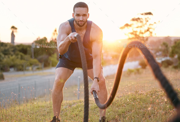 Work those muscles. Shot of a sporty young man doing heavy rope training  outside. Stock Photo by YuriArcursPeopleimages