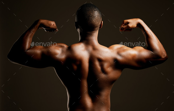 Rearview studio shot of a fit young man flexing against a black background  Stock Photo by YuriArcursPeopleimages