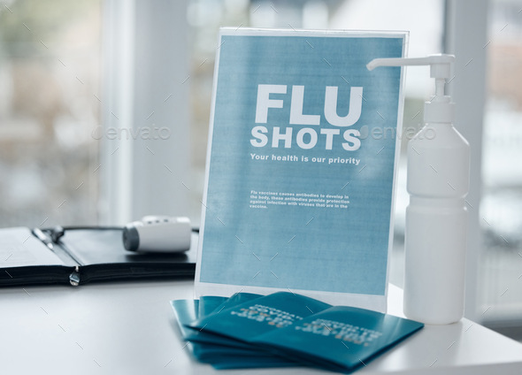 Get your flu shot this winter. Shot of a sign, pamphlets and hand sanitiser on a desk in an office.