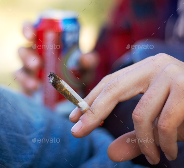 Puffing the day away. Shot of a unrecognizable person smoking a large marijuana joint.