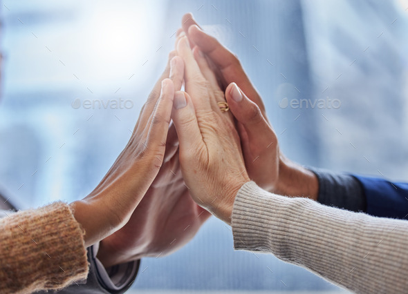 Together we can do this. Shot of a group of businesspeople high fiving each other.