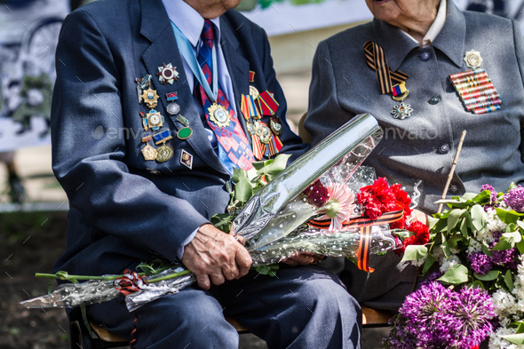 Saying goodbye to a dear friend. Cropped image of two war veterans holding flowers at a funeral.