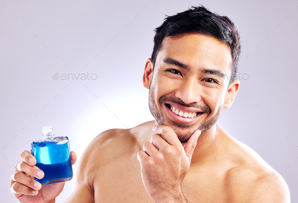 Everyone likes to smell good. Studio shot of a handsome young man applying aftershave.