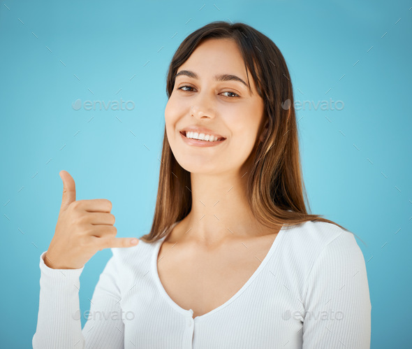 Call me. Studio shot of a young woman holding her hand out and showing the hang  ten sign. Stock Photo by YuriArcursPeopleimages