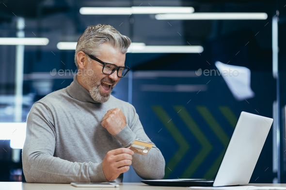 Happy and smiling businessman in office making bank transfer and online purchase in online store