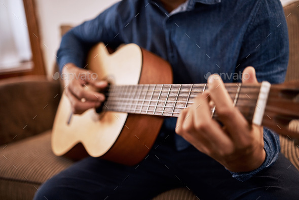 Time to tune up these skills. Shot of a man practicing his guitar skills at home.
