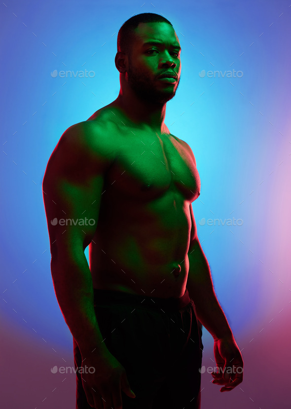 Dont act like youre not impressed. Studio shot of a man posing shirtless against a neon background.