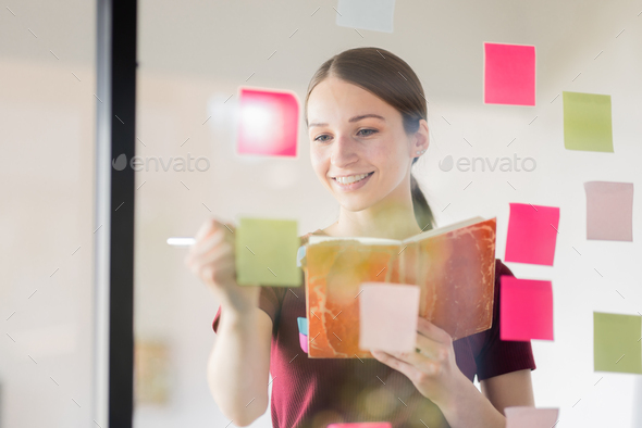 Business woman meeting at office and use post it notes in glass wall to share idea. Brainstorming bu