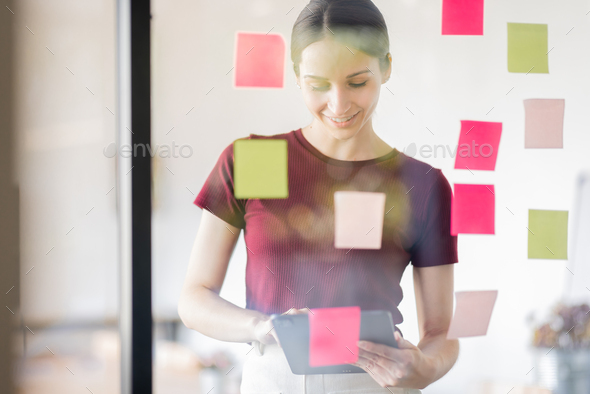 Business woman meeting at office and use post it notes in glass wall to share idea. Brainstorming bu