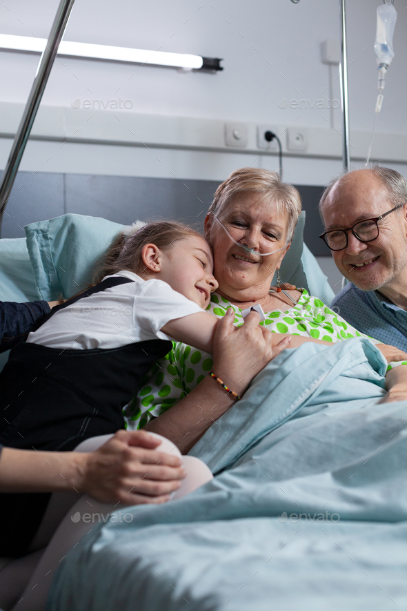 Grandfather, little girl visiting sick elderly woman in hospital
