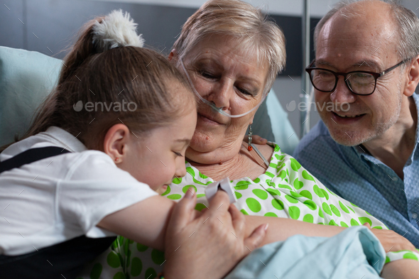 Girl hugging happy grandparents at medical clinic room