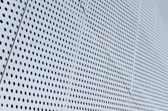 Diagonal view of metall grilles and round holes in metal surface, perforated panels for background.