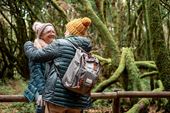 Lovely senior couple enjoying nature outdoors in a mountain forest with moss covered trunks