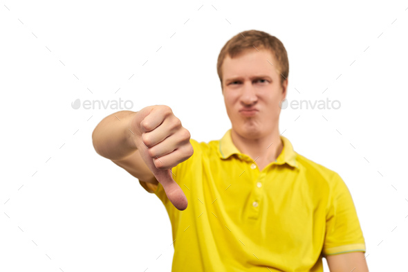 Unhappy annoyed man in yellow T-shirt showing thumbs down gesture isolated on white background