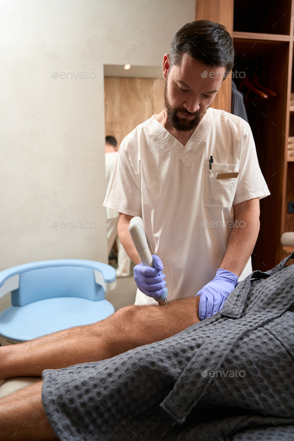 Qualified male doctor running procedure for pain management of patient