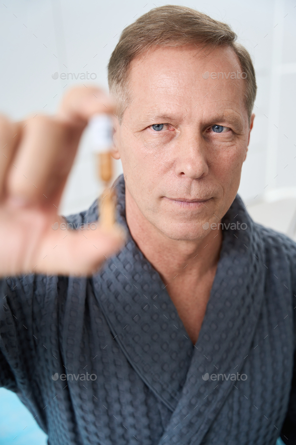 Serious man holds ampoule with modern medicine in his hands