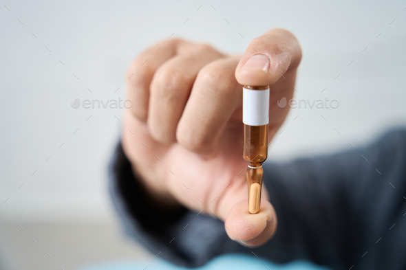 Close up of man holds an ampoule with medicine in his hand