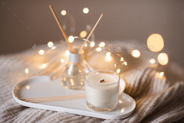 Organic soy wax candle with home diffuser in room over light Stock Photo by  morrowlight