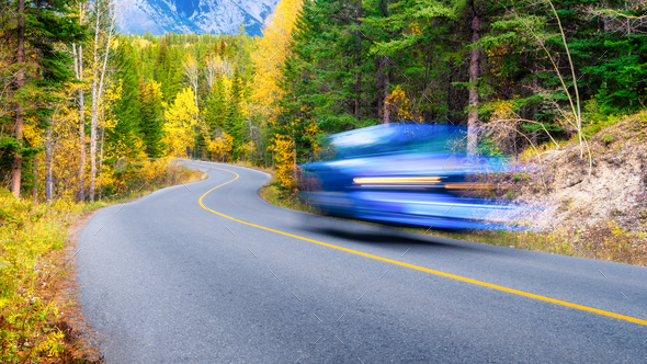 The road through the forest. Fast car. Transportation. Asphalt road and turns between trees.