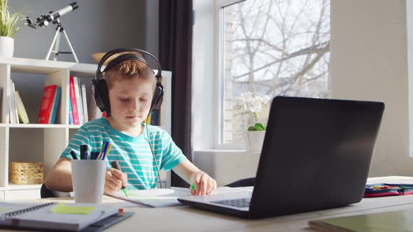 Boy is Doing  Homework at the Table. Cute Child is Learning at Home. alt