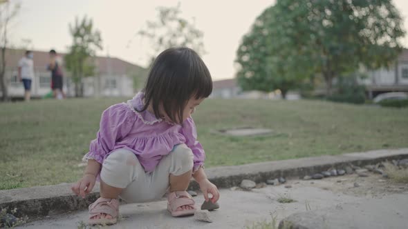 Baby girl sitting and playing a stone in the garden. Happy baby girl. alt