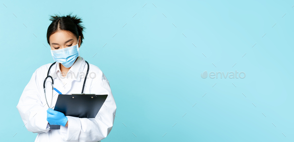 Image of korean doctor, female nurse in medical face mask, writing down patient information