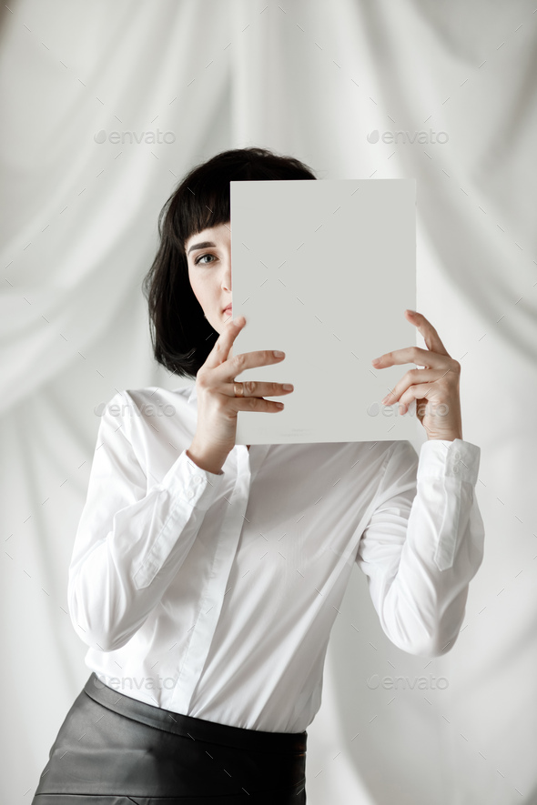 beautiful young businesswoman with dark short hair holding a magazine, book with mock up. girl