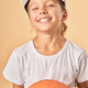 Cheerful female child in cap holding basketball ball - PhotoDune Item for Sale