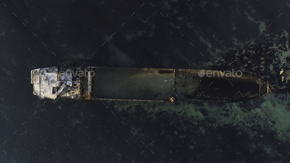 Aerial top view for wrecked ship along the rocky coast in blue water. Shot. Old sunk boat near sea